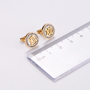 Macro shot of gold stainless steel stud earrings with crystals and Roman numerals