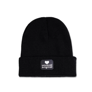 Detail of black knitted beanie featuring a heart logo patch and unusual original text