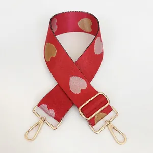 Detailed view of red nylon bag strap with pink woven hearts and gold lobster clasps