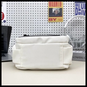 Detail of white canvas square crossbody bag with black mesh zipper top and side stitching
