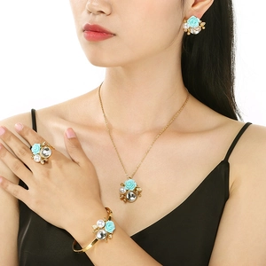 Close-up of elegant gold jewelry set with blue roses and pearls worn by a model