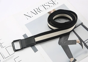 Detail of striped canvas belt with black metal double D-rings and leather reinforcement