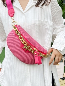 Pink woven fanny pack with gold chain and metal horse charm shown on a female model
