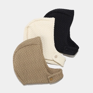 Close-up of quilted winter aviator hats with snap buttons in three neutral colors