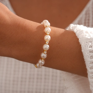 Détail macro du bracelet en perles avec espaceurs dorés en strass sur le poignet