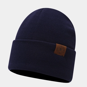 Detail of navy knit beanie showing thick ribbed texture and leather compass logo patch