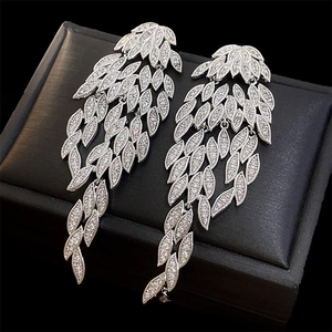 Macro shot of silver tassel earrings with white zircon feathers on a black leather surface