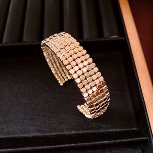 Detail of a multi-layer gold metal woven bangle with circular link patterns on velvet