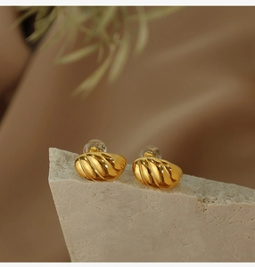 Detailed view of gold C-shaped ribbed earrings on a textured stone display