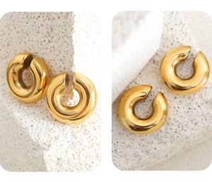 Macro detail of high-polished gold geometric hoop earrings on natural white stone base