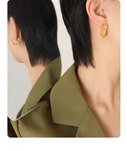 Detailed view of twisted gold-plated hoop earrings worn with an olive green blazer