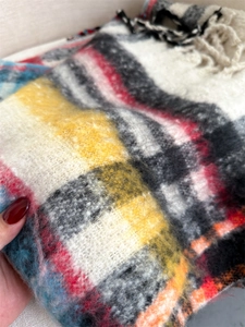 Close-up of thick plaid scarf featuring soft fleece texture and detailed fringe edges