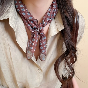 Close-up of a vintage brown floral silk scarf necklace paired with a striped shirt