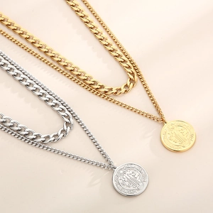Detail of gold and silver chunky double layer necklaces with Saint Benedict medal pendants