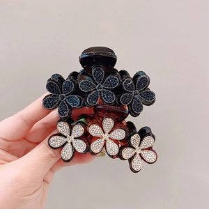 Dettaglio di due mollette per capelli floreali con strass blu scuro e trasparenti eleganti