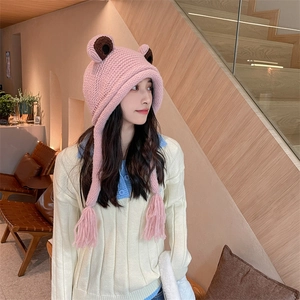 Nahaufnahme der rosa Frosch-Strickmütze mit Ohrenklappen und dekorativen Quasten