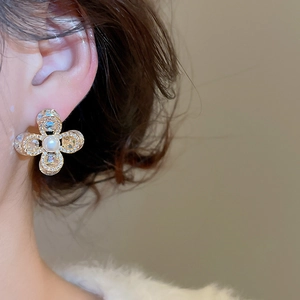 Gros plan détaillé d'une boucle d'oreille fleur avec pétales en cristal et perle blanche