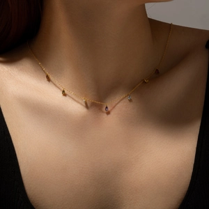 Elegant gold necklace with multi-colored teardrop pendants on female collarbone