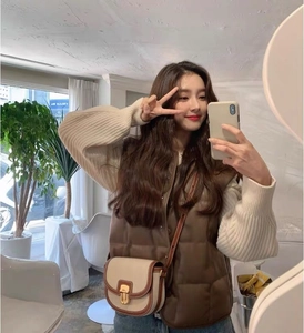 Foto lifestyle di una borsa a sella bicolore beige e marrone con un gilet trapuntato