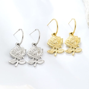Detailed view of gold and silver rose earrings with realistic flower petals on white background