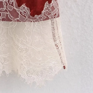 Elegant burgundy satin skirt with delicate cream lace trim detailing shown in close-up
