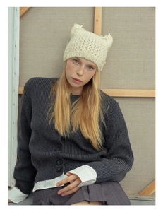 Detail of cream white cat ear knit hat with bow and coarse hand-knitted wool texture