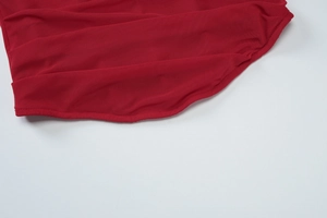 Close-up of red mesh knit fabric showing detailed pleated texture and fine edge stitching