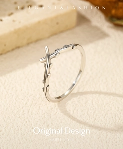 Detailed view of S925 sterling silver olive branch cross ring on a textured background