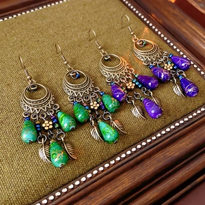 Detail of vintage bronze flower earrings with teardrop beads and leaf pendants on burlap