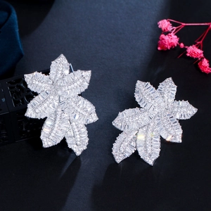 Macro shot of silver leaf earrings with shimmering cubic zirconia and floral background