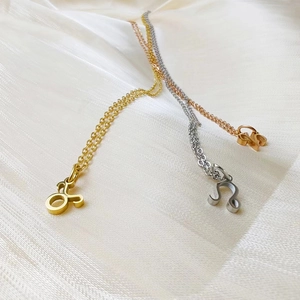Close-up of gold, silver, and rose gold zodiac pendant necklaces on soft white silk