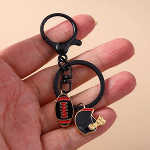 Rugby themed keychain featuring a football and helmet charm held in hand on beige background
