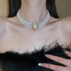 Detailed view of luxury three-layer pearl necklace with gold oval diamond-set clasp