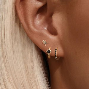 Detailed view of sterling silver star and heart earring set with black gemstones on ear