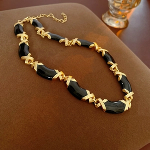 Detail of vintage necklace with gold X-links and black curved accents on suede stand