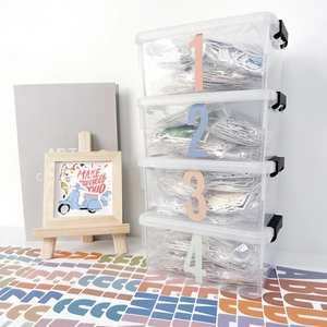 Detail of clear 4-tier storage boxes with numbered labels for alphabet stickers