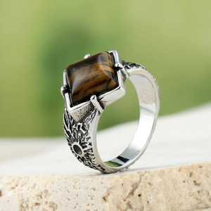 Macro view of men's vintage stainless steel ring with brown tiger eye stone on stone base
