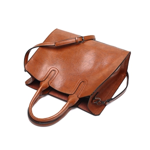 Top-down view of brown leather handbag with twin handles and adjustable shoulder strap
