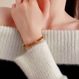 Close-up of a natural brown tiger eye beaded bracelet with gold accents on a wrist