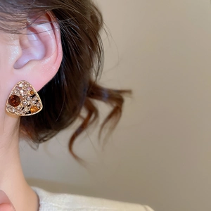Close-up of vintage triangle earrings with brown and champagne crystals on a model's ear