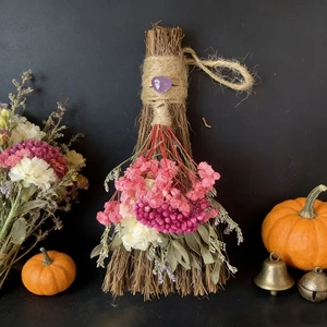 Close-up of decorative straw broom with purple crystal and colorful dried flowers