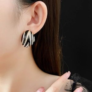 Macro shot of vintage oval earring with black enamel and gold stripes on model ear