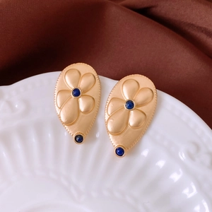 Detail of vintage matte gold water drop earrings with blue stone and floral relief