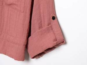 Detail of dusty pink jacket sleeve showing natural linen texture and black resin button
