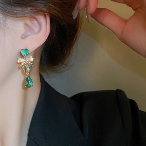 Boucles d'oreilles nœud vintage avec zircons verts en forme de cœur sur mannequin