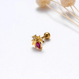 Macro detail of gold spider stud earring with red gemstone and clear crystal head