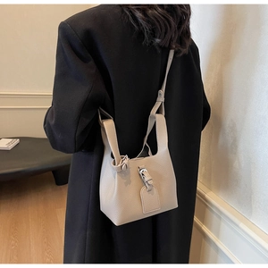 Vue détaillée du sac seau beige montrant la texture grainée et les détails argentés