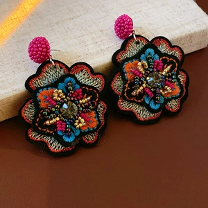 Macro detail of handmade floral bead embroidery earrings with colorful crystal accents
