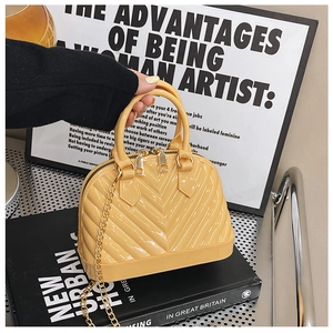 Detail view of yellow jelly shell bag with glossy finish and gold chain handle
