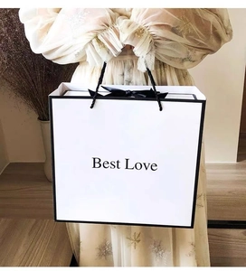 Minimalist white gift bag with black trim and Best Love text held by a model